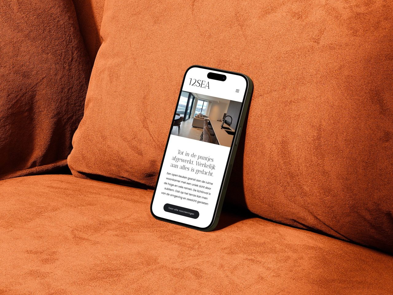 Smartphone op een oranje bank met website open.