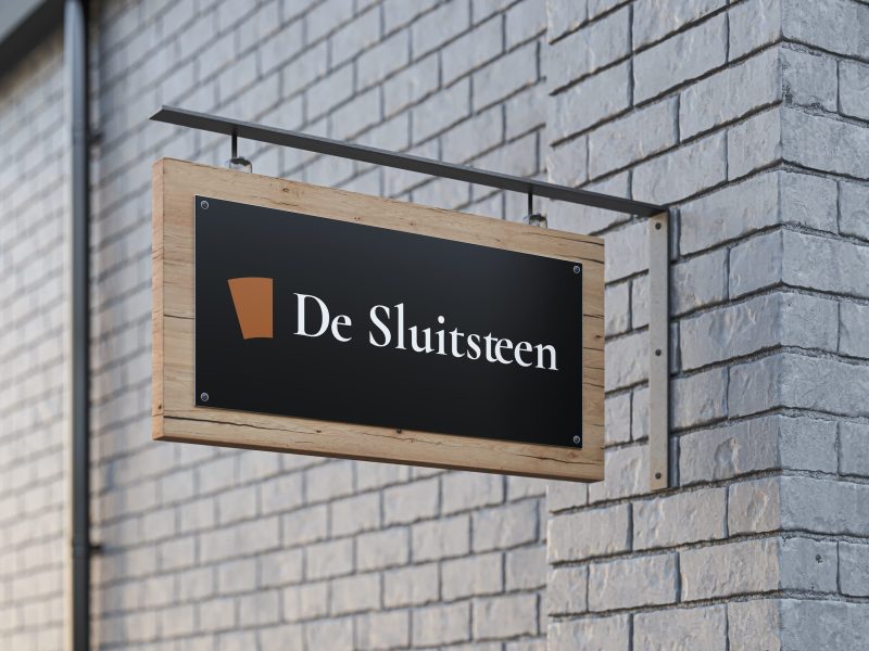 Bord met tekst 'De Sluitsteen' aan muur.